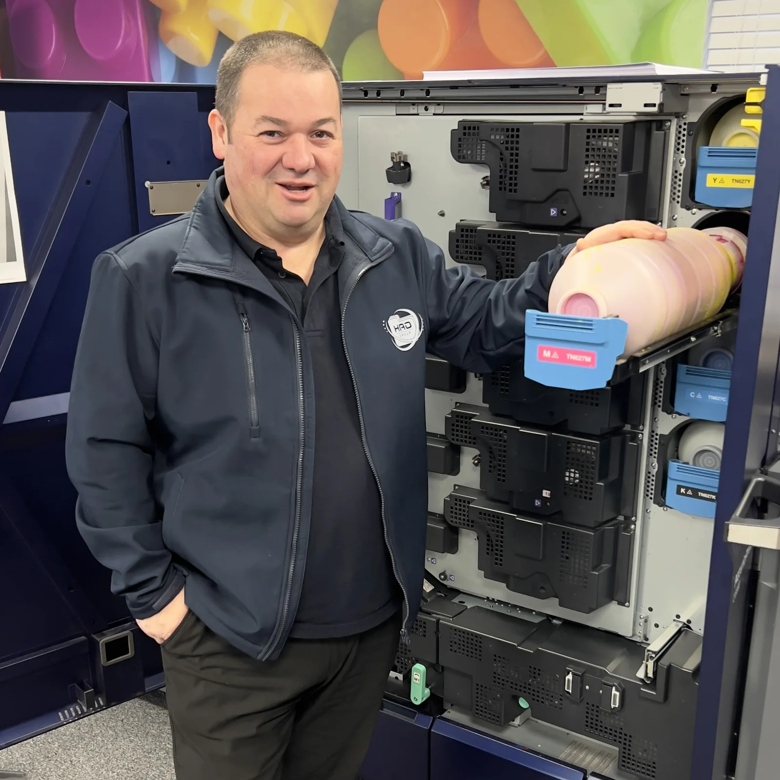 HAD-COPY team member standing beside a professional colour print device