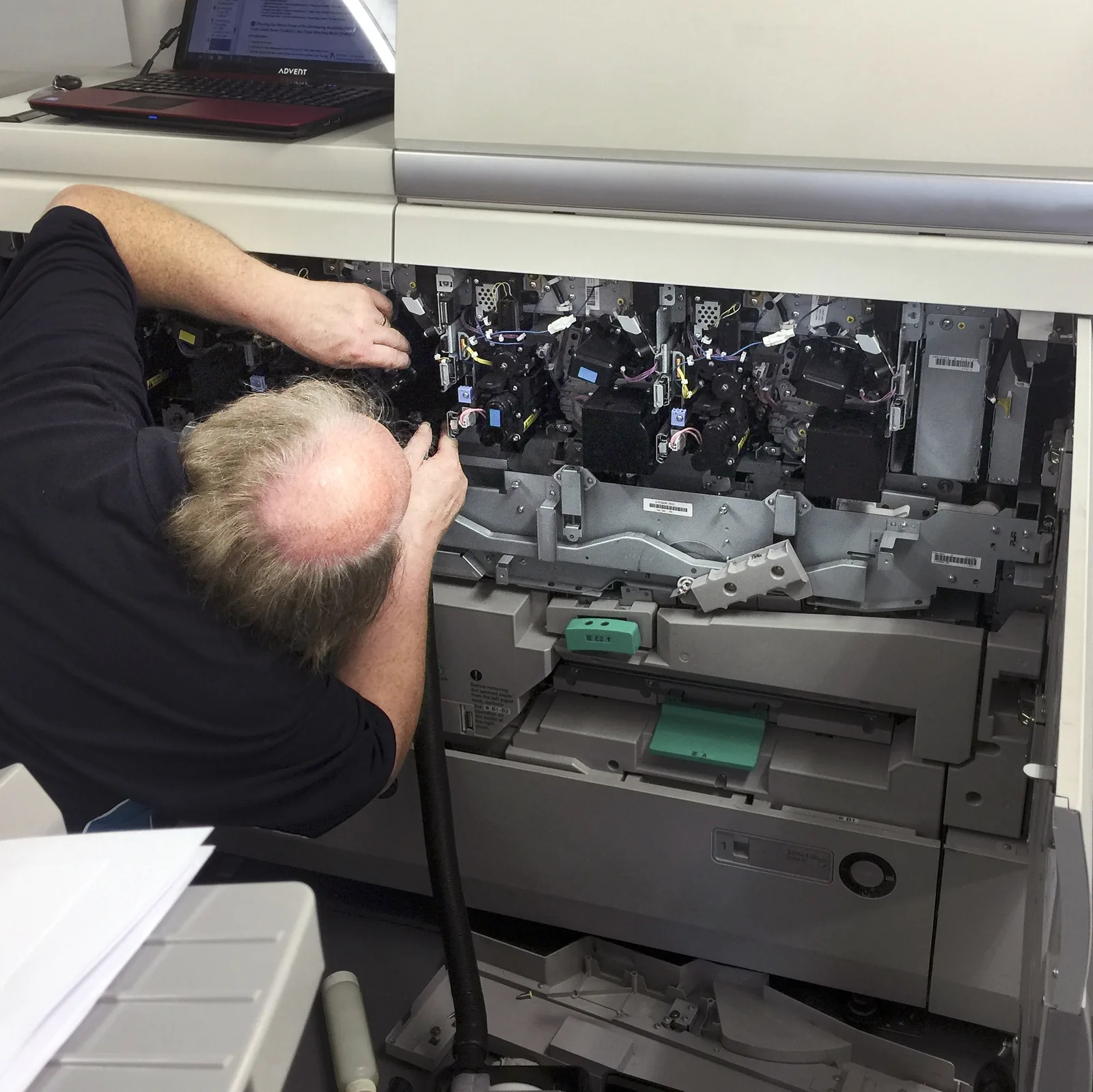 A HAD-COPY engineer carefully inspecting and supporting a professional photocopier